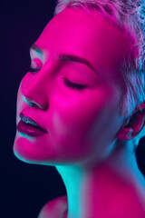 Close up. Portrait of female fashion model in neon light on dark studio background. Beautiful caucasian woman with trendy make-up and well-kept skin. Vivid style, beauty concept. Close up. Copyspace