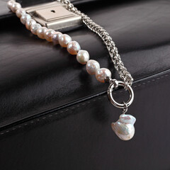 Women`s silver baroque pearl necklace with pendant on male black leather case