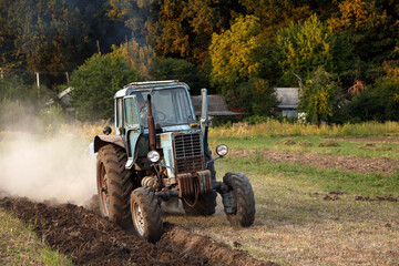 Naklejka premium an old tractor plowing a field 