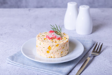 Crab salad with corn and eggs on a white plate. Serving in portions. Traditional Russian salad. Close-up.