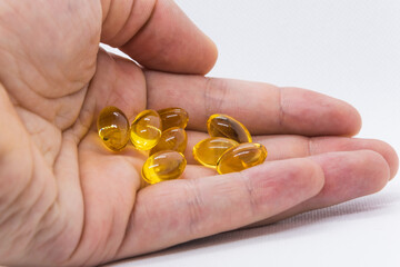 Yellow capsules scattered in a hand on a white background