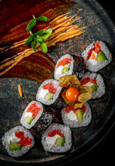sushi roll with salmon, avocado in plate on black wooden table background