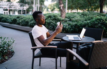 Busy black man using smartphone in park cafe