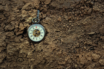 Fototapeta na wymiar vintage pocket watch on rough earth background. concept of past or future tense. time and earth. copy space