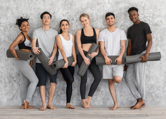 Group Training. Sporty Men And Women Posing With Yoga Mats Near Wall