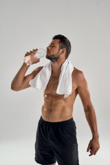 Feeling thirsty after workout. Vertical shot of young handsome muscular man with towel on his...