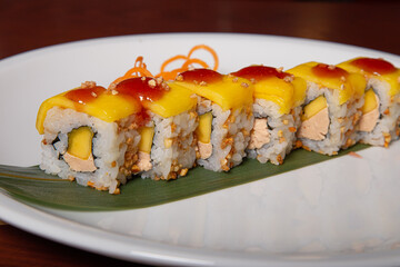 Mango sushi, foie gras, peanut and mango sauce served on a white plate. Japanese cuisine