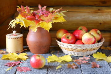 Fresh apples on a wooden table among autumn foliage.