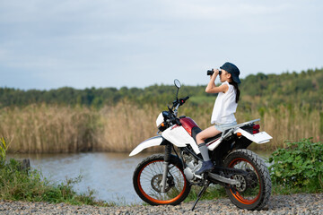 Fototapeta na wymiar オフロードバイクに乗って双眼鏡で遠くを見る女の子