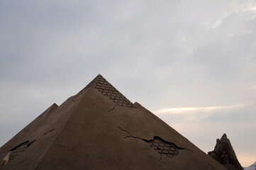 Sand sculpture of  pyramid against the sky.