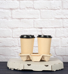 white cardboard box with pizza and disposable paper cups with coffee in holder