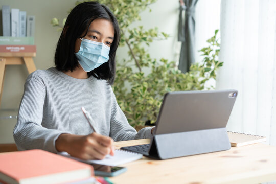 Asian woman wear medical mask and learning online with tablet at home