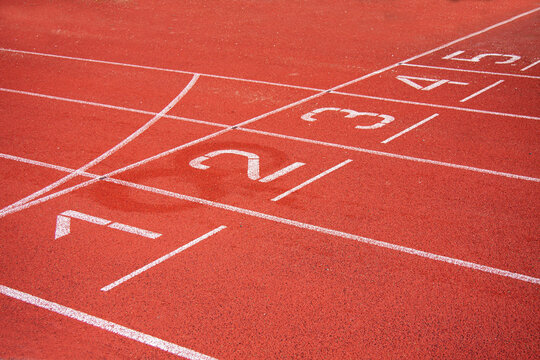 Athletic running track in a stadium with start point positions numbers one two, three, four five. No people. © Ole