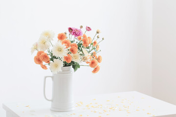chrysanthemum flowers in white jug on background white wall