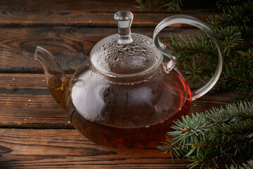 Christmas wooden background with a teapot of hot tea and fir branches.