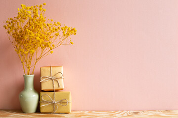 Gift boxes with yellow baby's breath, gypsophila dry flowers on wooden table with pink background