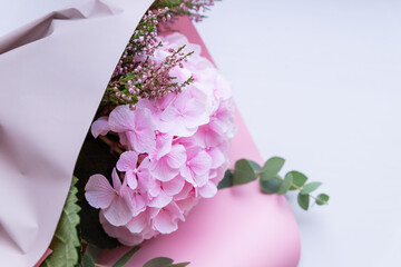 Luxurious flower arrangement with pink hydrangea, eucalyptus,Heather in a pink paper on a white background. Greeting card. Holiday bouquet.fresh flowers, beautifully wrapped in paper