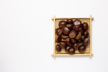 Chestnuts in wooden tray on white background. Autumn and winter snacks. top view, copy space