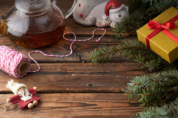 Christmas wooden background with toys,decor , teapot of hot tea and fir branches.