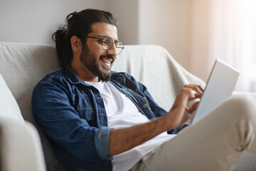 Happy western man checking social media on digital tablet at home