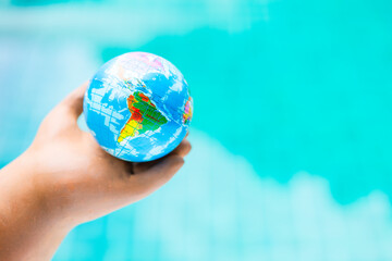 World map on global ball in clay hand over blurred blue water background, global warming and environmental