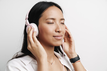 Photo of pleased asian woman listening music with headphones