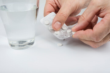 Man taking out a pill from a blister on a white