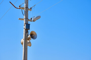 Speaker on the lighting pole. Means of warning in case of emergency. Against blue sky background copy space