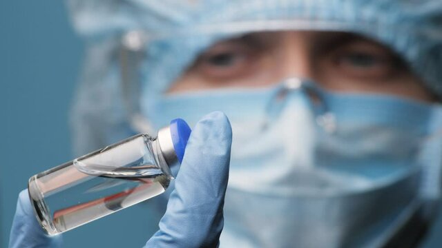 Close up of Nurse or Doctor look to newest vaccine. Scientist Epidemiologist looking at an ampoule with a vaccine against the virus holding it in hand, closeup. COVID-19, Novel Coronavirus 2019-nCoV