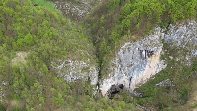 Flying above a waterfall and big cave entrance, Romania