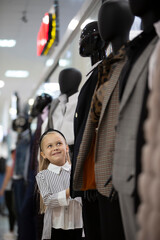 A little girl in the middle of a dummy in a store.