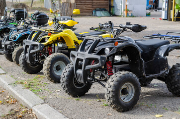 A group of random ATVs in a line outdoors.