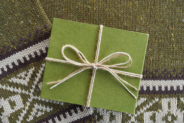 Green cardboard gift box on knitted woolen background