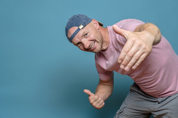 Smiling man beckons to somewhere by making an inviting gesture with one hand, and with the other he...