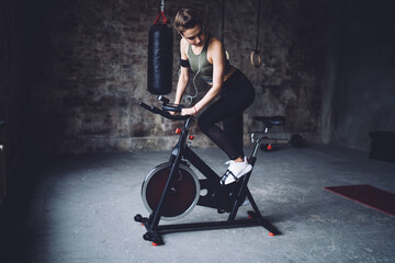 Fototapeta na wymiar Fit sportswoman training on cycling machine in studio