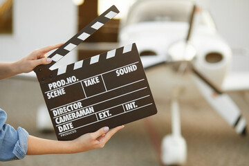 Close up of female hands holding movie clapperboard during the production of short film. Focus on...