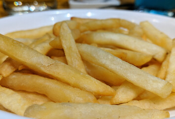 A white plate full of delicious french fries macro isolated snack closeup
