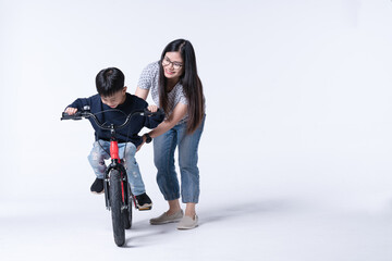 Obraz na płótnie Canvas Asian mother teach her son to ride a bicycle