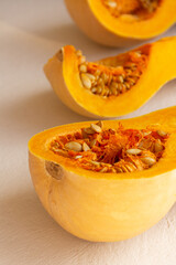 Fresh organic pumpkin cut into pieces on light concrete background