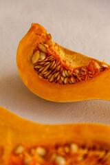 Fresh organic pumpkin cut into pieces on light concrete background