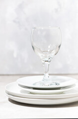 stack of clean white plates and a wine glass. serving element, vertical