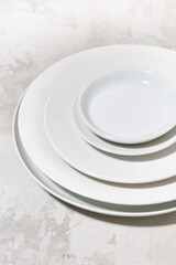 stack of clean white plates on white background, vertical closeup