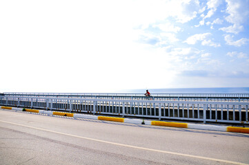 A woman cycling on the road by the sea.