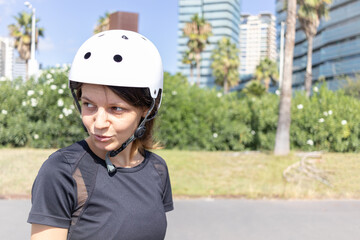 Young roller skater caucasian woman in the white helmet and black sporty clothes on a sunny day in the skatepark, urban environment
