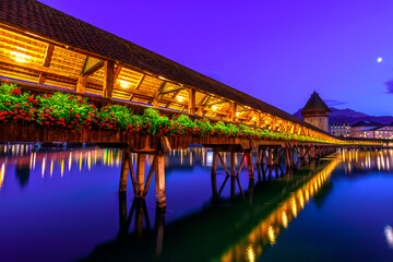 kapellbrucke historic flowered wooden Chapel Bridge with Water Tower reflects over Reuss river on Lake Lucerne illuminated at night. Scenic Lucerne, city of bridges, Canton of Lucerne, Switzerland.