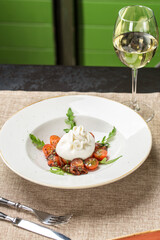 Cheese collection burrata cheese ball with fresh tomatoes and glass of white wine on the table at restaurant
