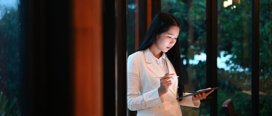 Young female using mock up digital tablet on workspace in modern office.