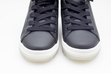 Pair of new black sneakers with white sole on white background