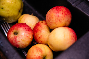 
Wet ripe apples in the black kitchen sink. Cooking.
