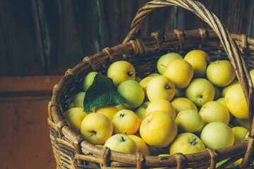 green apples in a knitted basket on a wooden background